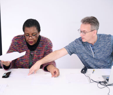 Zwei Personen besprechen Texte an einem Tisch Zwei Personen besprechen Texte an einem Tisch